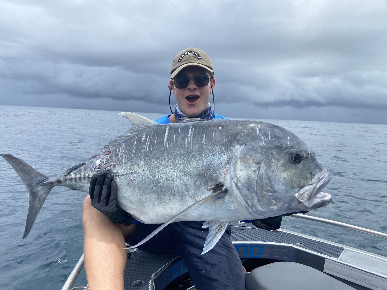 A giant trevally held up on deck